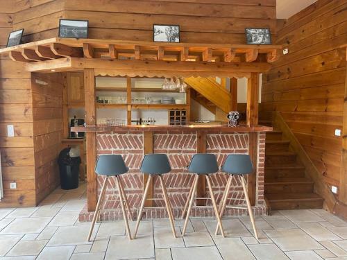 a bar in a wooden cabin with four stools at Logement 6 personnes avec SPA in Essômes-sur-Marne