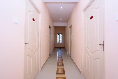un pasillo con paredes rosas, puertas blancas y suelo en OYO Flagship Viswa Towers, en Madurai