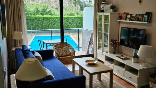 a living room with a blue couch and a view of a pool at Ladeira in Baiona
