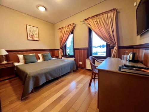 a bedroom with a bed and a desk and two windows at Harmony Park Countryside Villas & SPA in Prienai