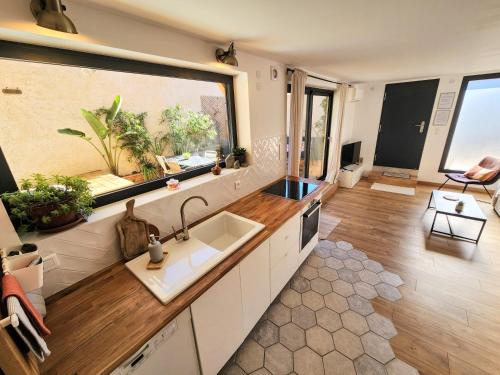 uma cozinha com um lavatório e uma grande janela em Cocon Nature Montpellier - Jacuzzi & Sauna - 300m du Tramway em Castelnau-le-Lez