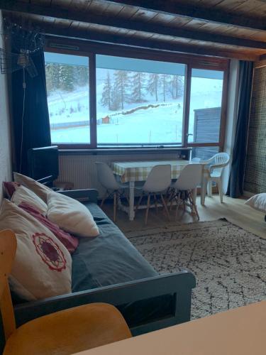 un salon avec un lit, une table et des chaises dans l'établissement Studio pied des pistes - Carlines, à Uvernet