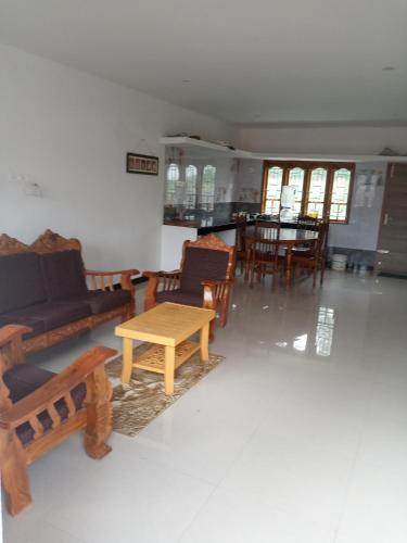 a living room with a couch and a table and chairs at Sai Trishuul home stay in Ooty