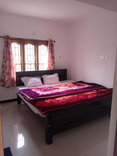 a bedroom with a bed with a red blanket on it at Sai Trishuul home stay in Ooty