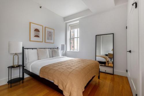 a white bedroom with a bed and a mirror at FiDi 1br w fitness center nr freedom tower NYC-1340 in New York