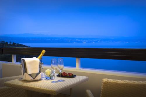 a table with wine glasses and a bottle on a balcony at Hotel Excelsior - Liburnia in Lovran