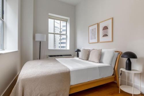 a bedroom with a bed with white sheets and a window at FiDi 1br w 3-story gym doorman game room NYC-1339 in New York