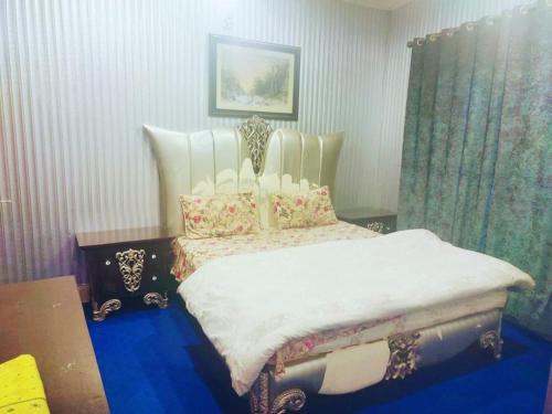 um quarto com uma cama com lençóis brancos e almofadas em Rashk e Qamar em Murree