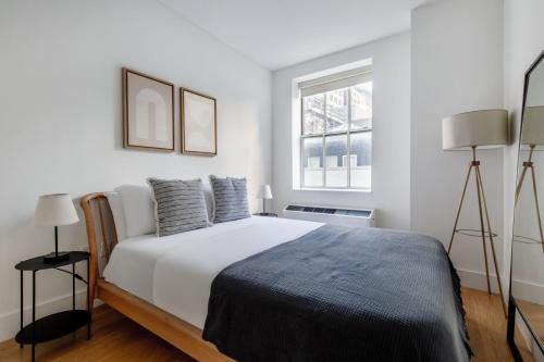 - une chambre blanche avec un grand lit et une fenêtre dans l'établissement FiDi 1br w gym doorman lounge nr park NYC-1344, à New York