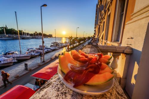 a plate of fruit sitting on a ledge next to the water at Summertime Apartments in Zadar
