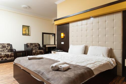 a bedroom with a large bed and two chairs at HOTEL ALBES in Prizren