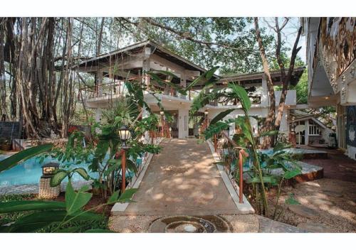 a large house with a swimming pool in front of it at The Singing Tree in Old Goa