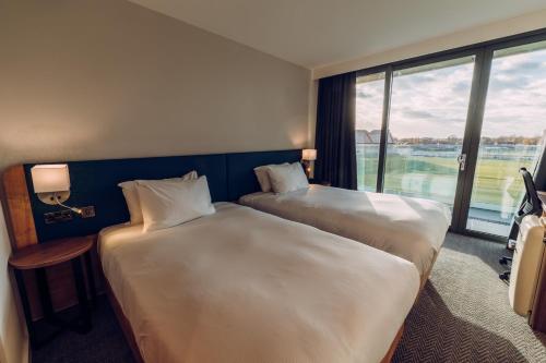 two beds in a hotel room with a large window at Hilton Garden Inn Manchester Emirates Old Trafford in Manchester