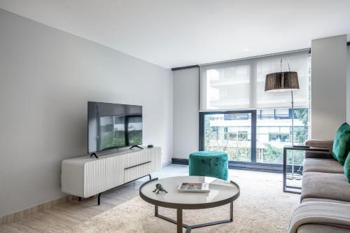 a living room with a couch and a tv at JVM 421, in Polanco by Blueground in Mexico City