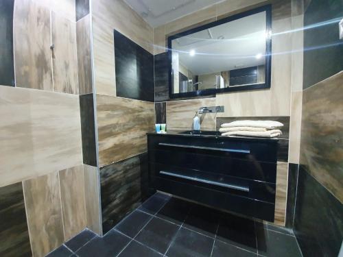 a bathroom with a black sink and a mirror at Harav Kuk Royal Suites - Alefimmoed in Jerusalem