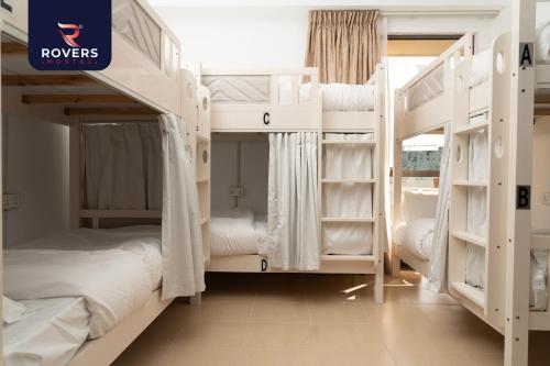 a room with two bunk beds with white bunkresses at Rovers Hostel Dubai in Dubai