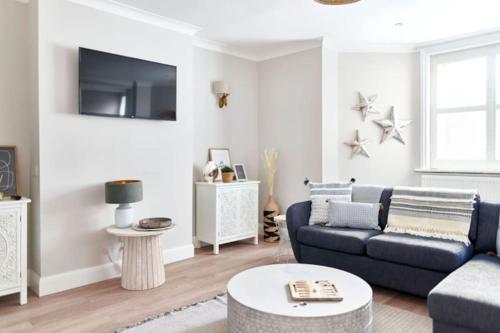 a living room with a blue couch and a table at Cute Beach House - 4 mins walk in Bournemouth