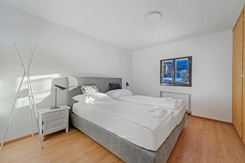 ein weißes Schlafzimmer mit einem Bett und einem Fenster in der Unterkunft Crest Alta 23 in Surlej