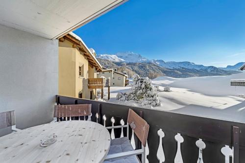 a table on a balcony with a view of snow covered mountains at Crest Alta 23 in Surlej