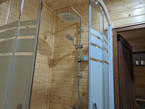 y baño con ducha y pared de madera. en Prime House Cottages en K'eda