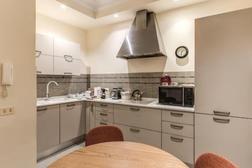 a kitchen with white cabinets and a table with chairs at Via Napoli Apartments in Rome