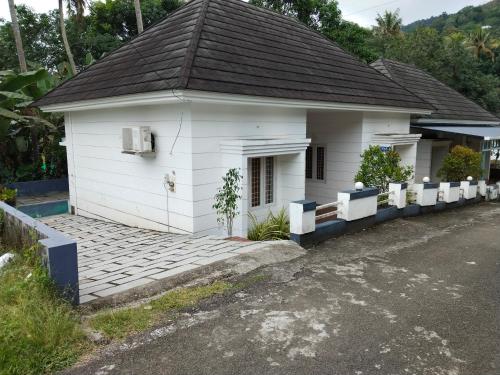 uma pequena casa branca com um telhado preto em Rose villas em Athirappilly
