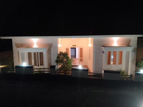 uma casa branca à noite com luzes acesas em Rose villas em Athirappilly