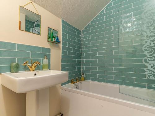 a blue tiled bathroom with a sink and a tub at 2 Bed in South Molton 78302 in Kings Nympton