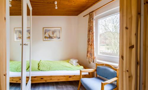 a bedroom with a bed and a chair and a window at Monteurzimmer an der Schlei in Rabenkirchen-Faulück