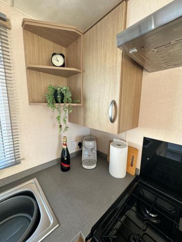 a kitchen with a sink and a clock on the wall at Bayview Bliss - Luxury Holiday Caravan - Northumberland in Newbiggin-by-the-Sea