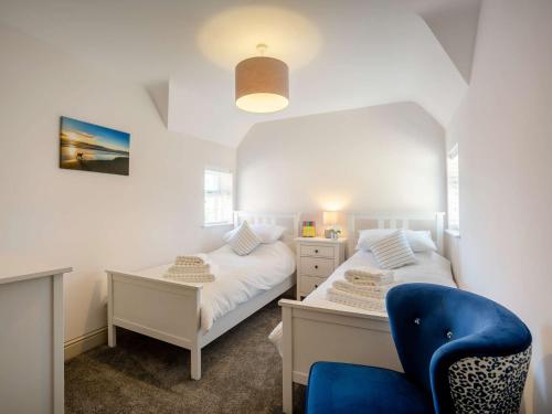 1 dormitorio con 2 camas y silla azul en 4 bed in Nr Druridge Bay 79370, en Hadston