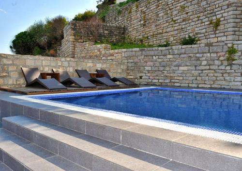 a swimming pool with lounge chairs next to a brick wall at Avala Resort & Villas in Budva