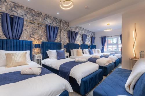 - une rangée de lits dans une chambre dotée de rideaux bleus dans l'établissement Patriot Bar Hottub-sleeps30, à Abbeyfeale
