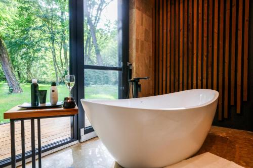 a large white bath tub in a bathroom with a window at Forestlux Vendégház in Zebegény