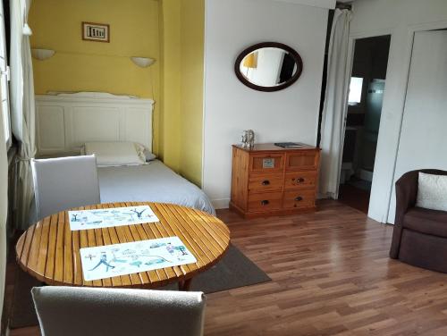 Un dormitorio con una cama, una mesa y un espejo. en La petite chapelle, en Honfleur