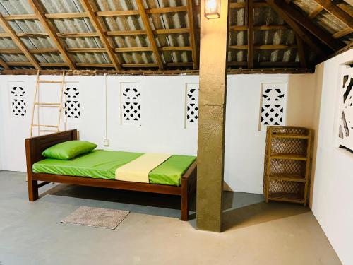 a room with a bed with green sheets and a ladder at Bay Vista-Yala in Kirinda
