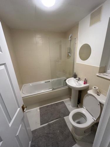 a bathroom with a toilet and a sink and a tub at 2 Bedroom Refurbished House in Curdworth