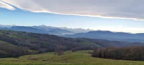 a green hill with trees and mountains in the background at Chambre Nature Mondavezan in Mondavezan