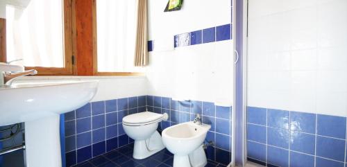 W wyłożonej niebieskimi kafelkami łazience znajduje się toaleta i umywalka. w obiekcie Villacelest Casa Vacanze Peschici w mieście Peschici