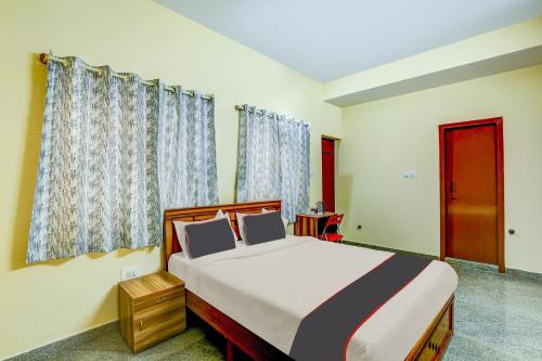 a bedroom with a large bed with blue curtains at Collection O Relax Stay Apartments in Bangalore