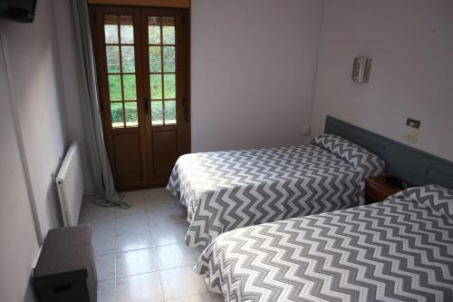 1 dormitorio con 2 camas, ventana y puerta en Alojamiento Monte y Mar, en La Isla