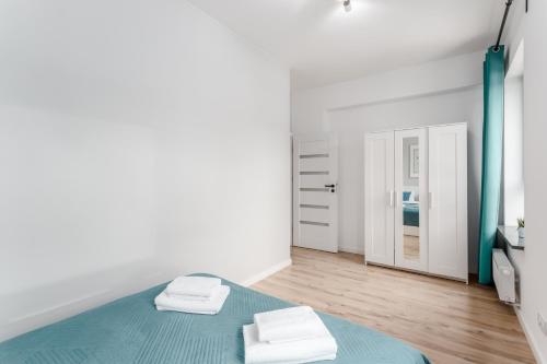 een witte slaapkamer met een blauw bed en 2 handdoeken bij Warsaw City Apartments Praga in Warschau