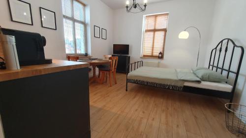 a bedroom with a bed and a kitchen with a table at Apartament Wieżyczka in Świdnica