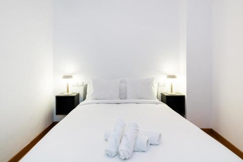 a bedroom with a white bed with two lamps at Piso junto a Mercado de San Agustín y Catedral en Granada in Granada