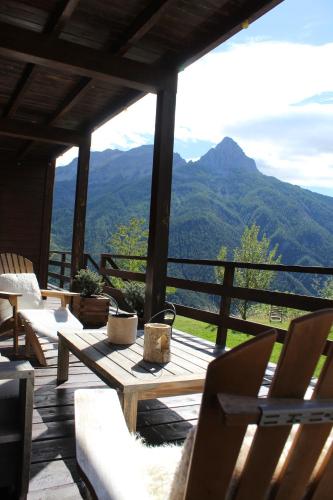 a porch with tables and chairs and a view of mountains at Chalet l'Aigle bleu in Uvernet-Fours