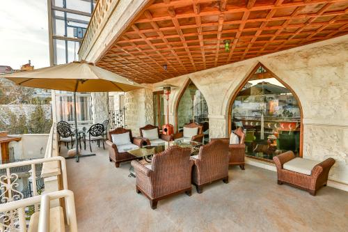 um pátio com cadeiras e mesas e um guarda-sol em Cappadocia Fairy Chimneys Minia Cave Hotel em Ortahisar
