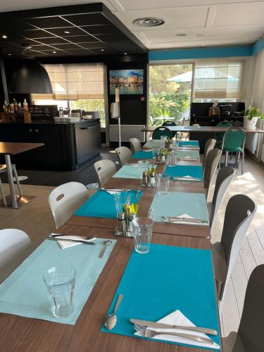 une grande salle à manger avec des tables et des chaises bleues dans l'établissement Kyriad Direct Marseille Ouest - Martigues, à Martigues