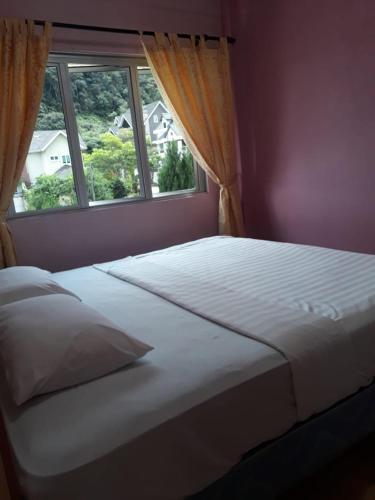 een slaapkamer met een groot bed en een raam bij Camlodge Apartments in Tanah Rata