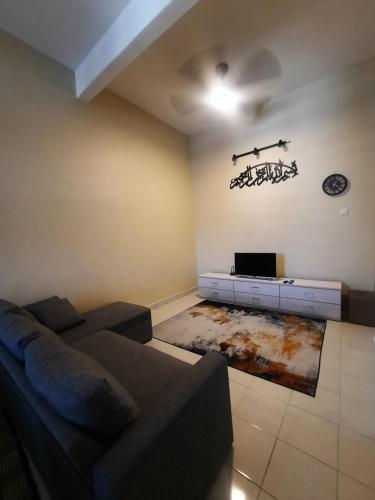 D'homestay Parit Buntar في باريت بونتار: غرفة معيشة مع أريكة وتلفزيون