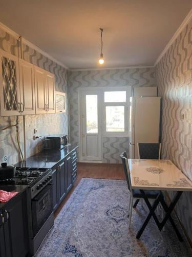 een keuken met een fornuis en een tafel. bij Apartment on Jeltoksan in Simkent
